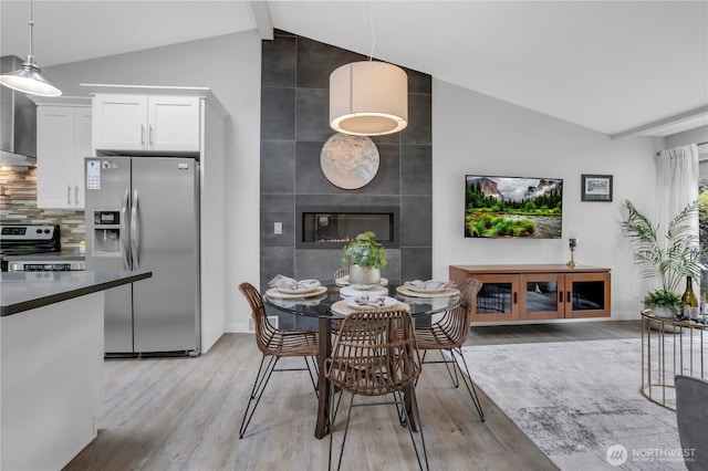 dining area with light wood-style floors, baseboards, and a fireplace