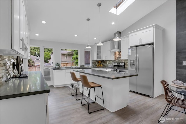kitchen with appliances with stainless steel finishes, dark countertops, a skylight, tasteful backsplash, and white cabinetry