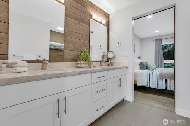 ensuite bathroom with wood walls, double vanity, tile patterned flooring, and recessed lighting
