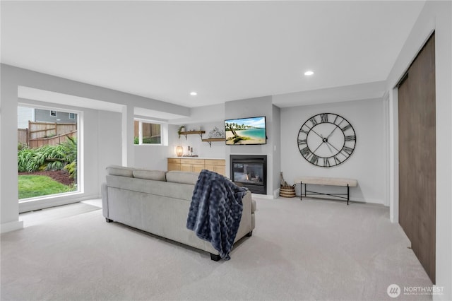 living room featuring carpet floors, a glass covered fireplace, recessed lighting, and baseboards