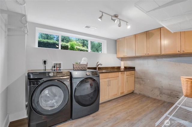 washroom with washer and dryer, light wood-type flooring, cabinet space, and rail lighting