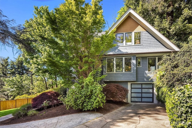 view of front of home with a garage, concrete driveway, and fence