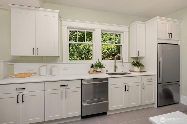 kitchen with appliances with stainless steel finishes, a sink, light countertops, and white cabinets