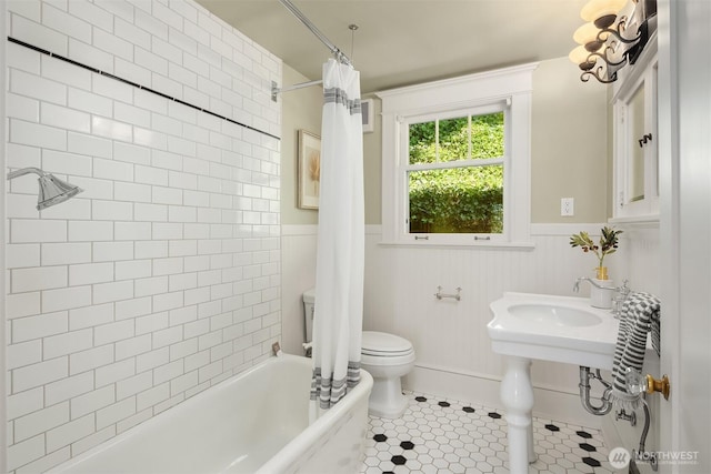 bathroom featuring toilet, a wainscoted wall, tile patterned flooring, and shower / tub combo with curtain