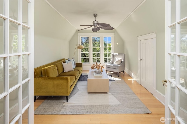 living area with wood finished floors, a ceiling fan, lofted ceiling, and baseboards
