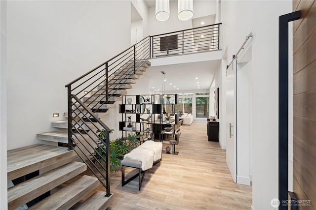 stairs featuring wood finished floors, a towering ceiling, and baseboards