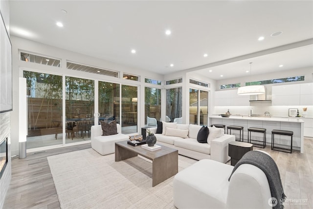 living area with light wood-style flooring, recessed lighting, and a glass covered fireplace