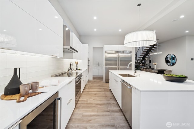 kitchen with modern cabinets, a sink, beverage cooler, high end appliances, and white cabinetry
