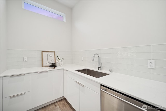 kitchen featuring a sink, dishwasher, white cabinetry, and decorative backsplash