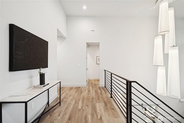 hall featuring light wood finished floors, baseboards, and recessed lighting