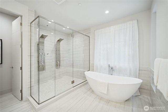bathroom with a soaking tub, a shower stall, and recessed lighting