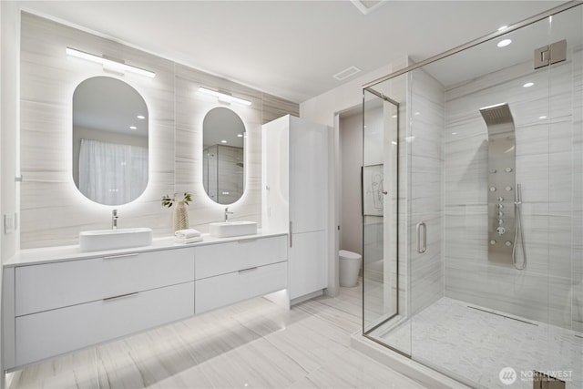 full bathroom with a shower stall, double vanity, tile patterned floors, and toilet