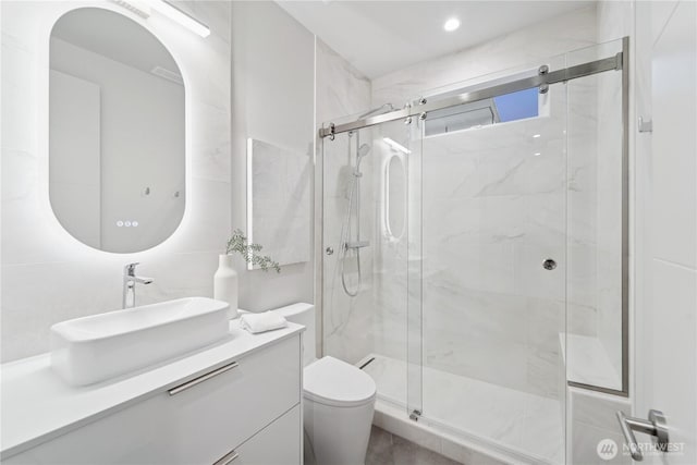 full bathroom featuring a marble finish shower, toilet, and vanity