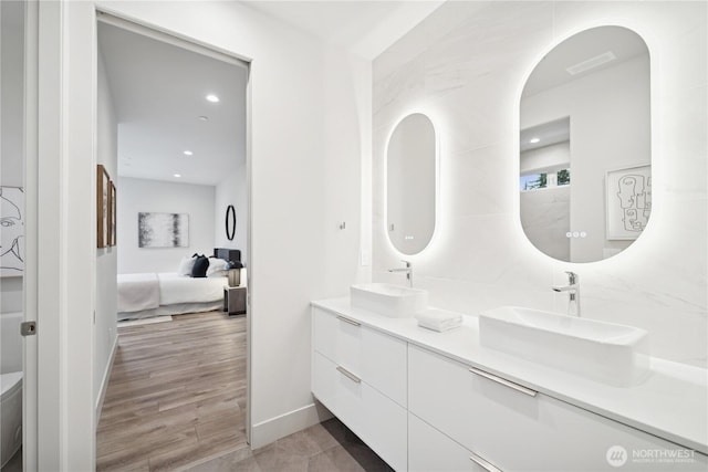 bathroom with ensuite bathroom, double vanity, baseboards, recessed lighting, and toilet