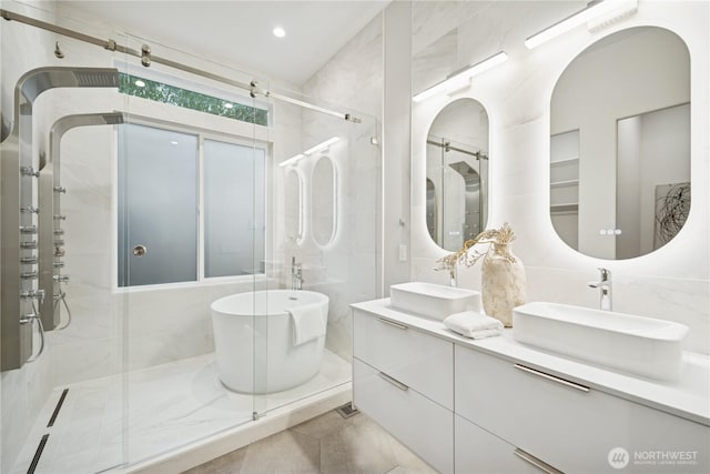bathroom with a shower stall, double vanity, a freestanding tub, and tile patterned floors