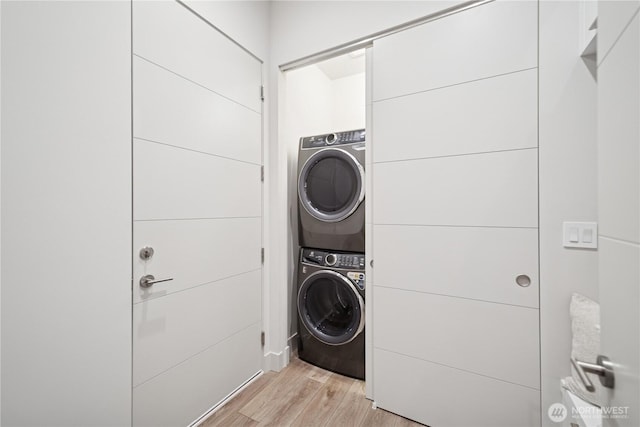 laundry room with stacked washer and clothes dryer, light wood finished floors, and a package area