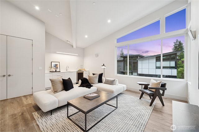 living area with light wood finished floors, beverage cooler, high vaulted ceiling, wet bar, and recessed lighting