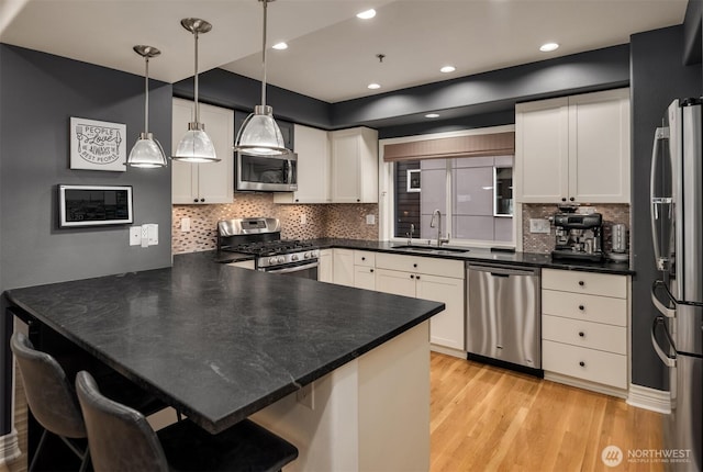 1416 6th Ave N, Seattle, WA 98109 - kitchen featuring appliances with stainless steel finishes, a sink, a peninsula, light wood finished floors, and white cabinetry