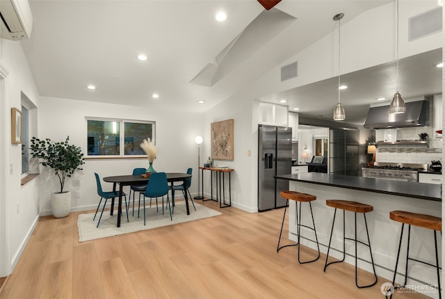 18906 32nd Ave NE, Lake Forest Park, WA 98155 - kitchen with appliances with stainless steel finishes, an AC wall unit, wall chimney exhaust hood, dark countertops, and a kitchen bar