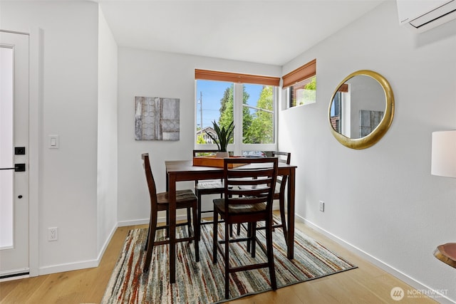 dining room with a wall mounted air conditioner, wood finished floors, and baseboards