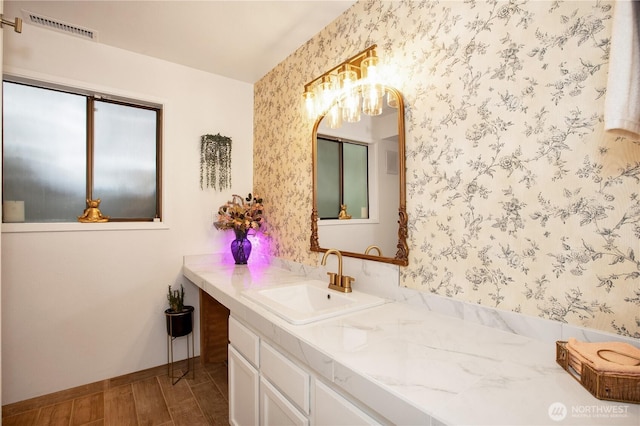 bathroom with wallpapered walls, a chandelier, wood finished floors, vanity, and baseboards