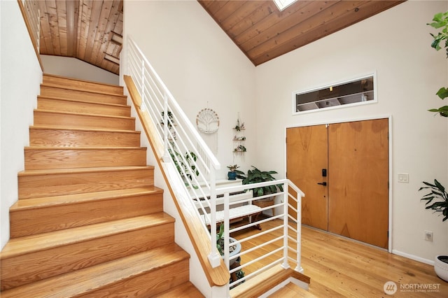 foyer featuring lofted ceiling, stairway, wood ceiling, wood finished floors, and baseboards