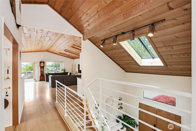 hall featuring wooden ceiling, vaulted ceiling, track lighting, wood finished floors, and a skylight