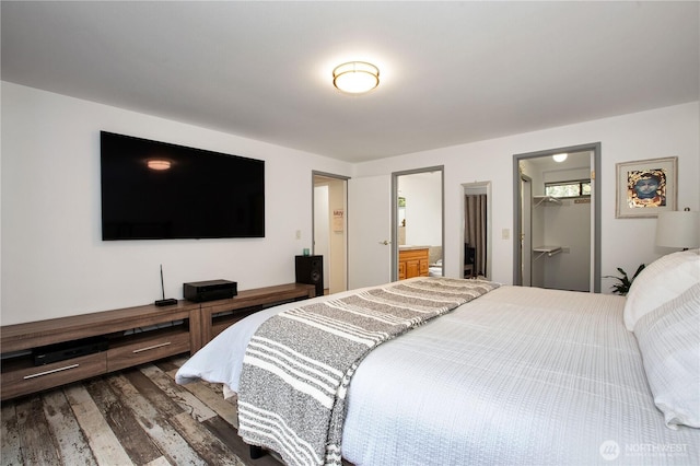 bedroom featuring wood finished floors, a walk in closet, ensuite bathroom, and a closet