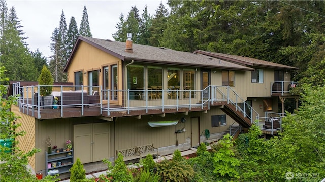 rear view of house with stairway, a wooden deck, and roof with shingles