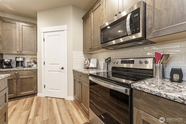 7135 S 13th St, Ridgefield, WA 98642 - kitchen featuring appliances with stainless steel finishes, light wood-style flooring, backsplash, and light stone countertops