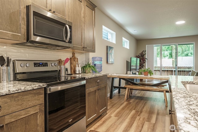 7135 S 13th St, Ridgefield, WA 98642 - kitchen with appliances with stainless steel finishes, decorative backsplash, light wood-style floors, light stone countertops, and recessed lighting