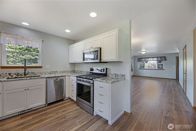 28540 74th Dr NW, Stanwood, WA 98292 - kitchen featuring appliances with stainless steel finishes, a sink, dark wood-type flooring, white cabinetry, and light stone counters