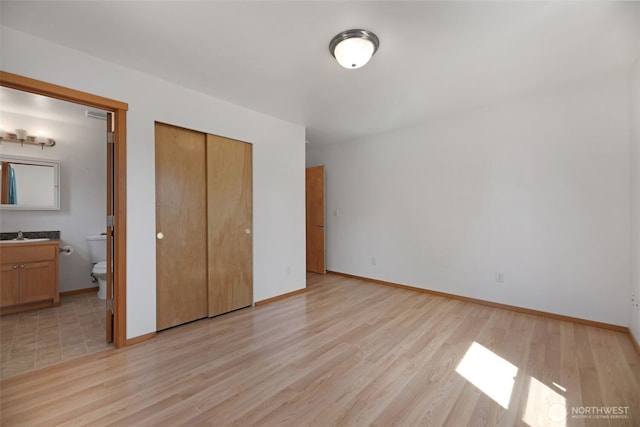 28540 74th Dr NW, Stanwood, WA 98292 - unfurnished bedroom featuring light wood finished floors, a closet, ensuite bathroom, baseboards, and a sink