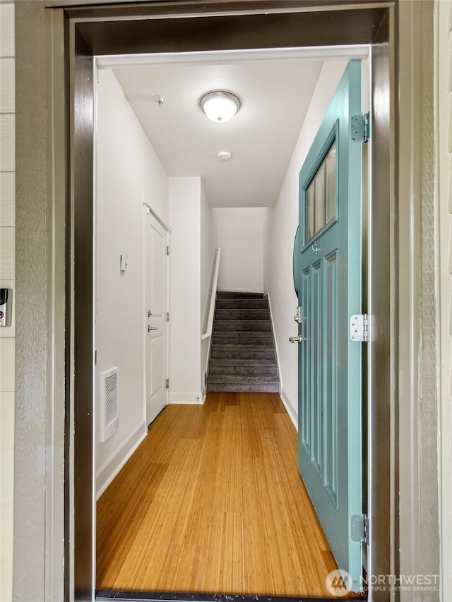 corridor with light wood-style flooring and stairway