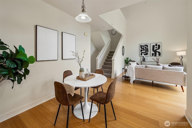 dining area with stairway, light wood-type flooring, and baseboards