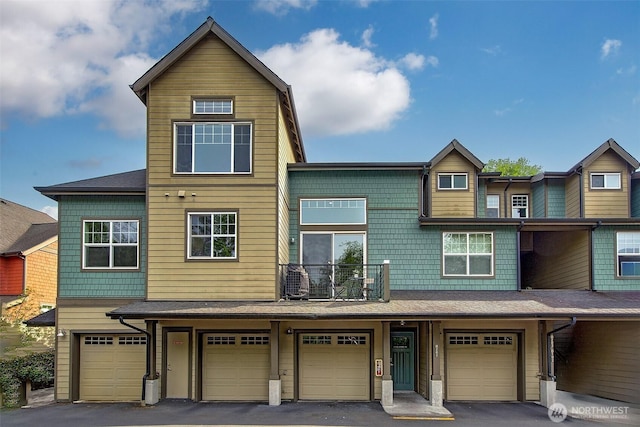 view of property featuring a garage, driveway, and a balcony