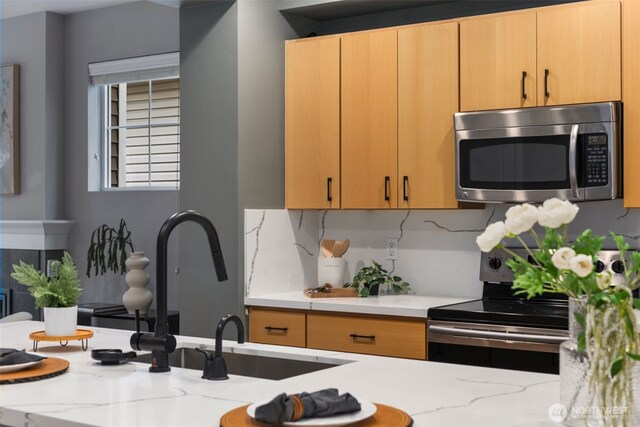 kitchen featuring appliances with stainless steel finishes, light stone countertops, and tasteful backsplash