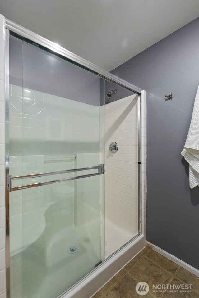 bathroom featuring a shower stall, tile patterned floors, and baseboards
