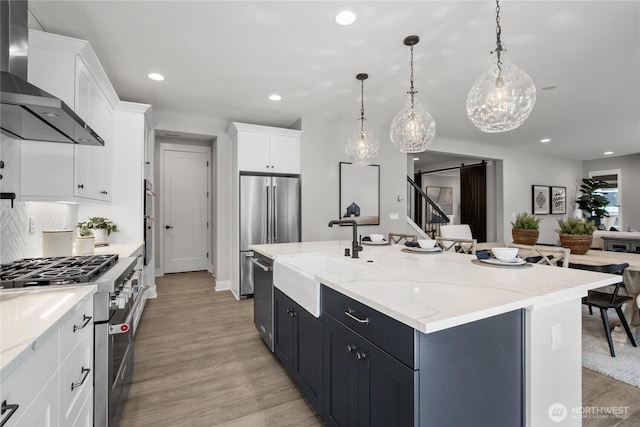 15321 204th Ave E Unit 56, Bonney Lake, WA 98391 - kitchen featuring wall chimney exhaust hood, a sink, high quality appliances, a kitchen island with sink, and recessed lighting