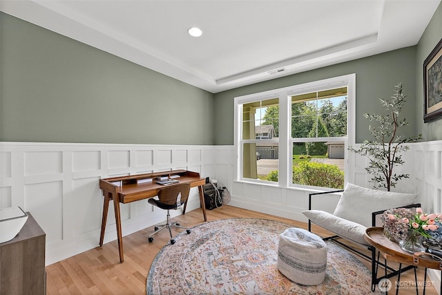 office area featuring a decorative wall, a wainscoted wall, light wood-style flooring, a raised ceiling, and recessed lighting