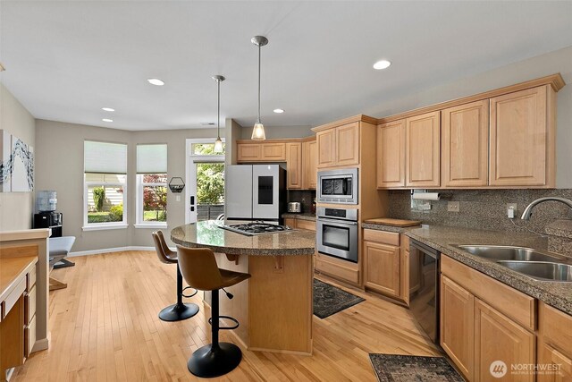 kitchen with appliances with stainless steel finishes, a sink, light brown cabinetry, light wood-style floors, and recessed lighting