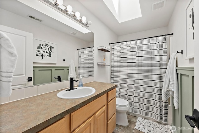 full bathroom with toilet, vanity, a skylight, tile patterned floors, and curtained shower