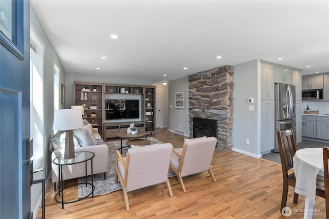 8155 28th Ave SW, Seattle, WA 98126 - living area featuring light wood-type flooring, recessed lighting, a stone fireplace, and baseboards
