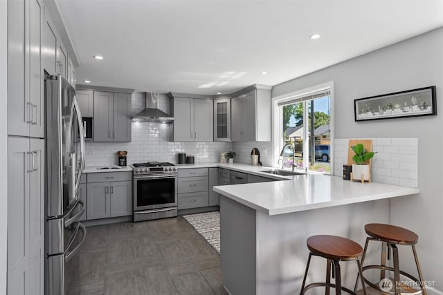 8155 28th Ave SW, Seattle, WA 98126 - kitchen featuring stainless steel appliances, gray cabinetry, wall chimney range hood, a sink, and a peninsula