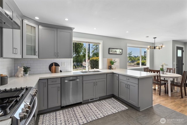 8155 28th Ave SW, Seattle, WA 98126 - kitchen with stainless steel appliances, gray cabinetry, a sink, a peninsula, and healthy amount of natural light