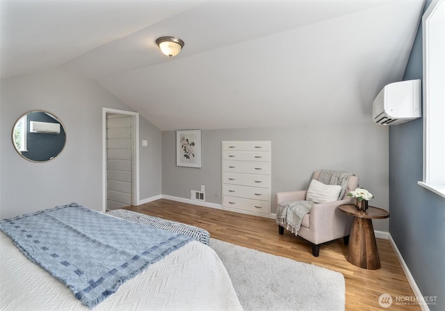 8155 28th Ave SW, Seattle, WA 98126 - bedroom featuring a wall mounted air conditioner, wood finished floors, vaulted ceiling, and baseboards