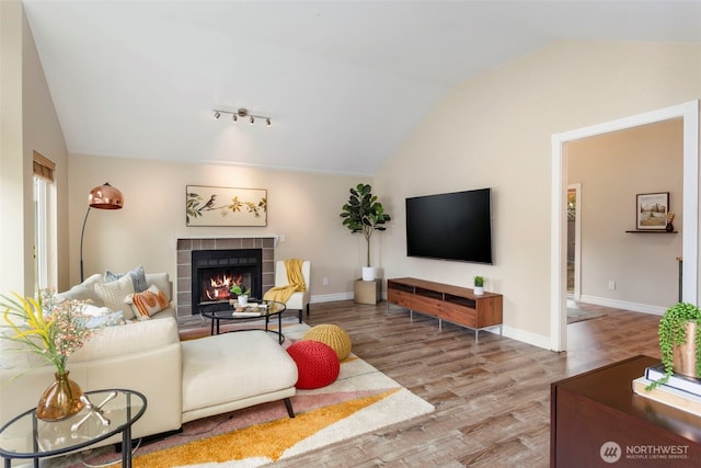 living area featuring lofted ceiling, a fireplace, wood finished floors, and baseboards