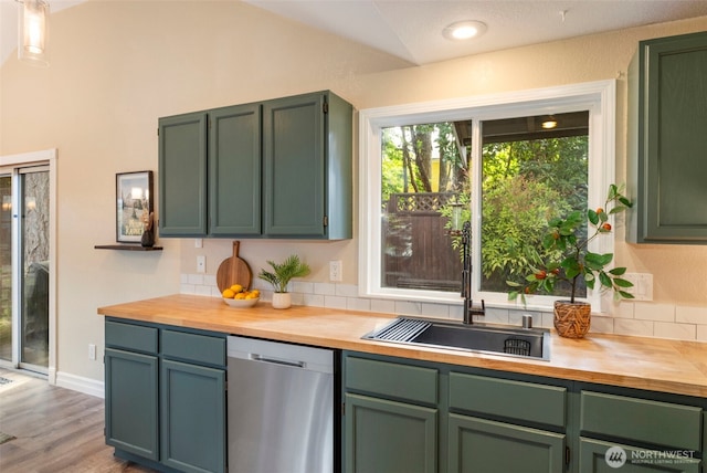 kitchen with wood counters, dishwasher, a sink, vaulted ceiling, and green cabinets