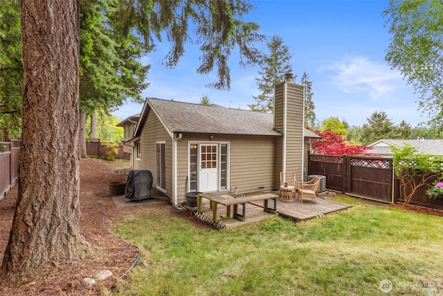 back of house with a deck, a chimney, central air condition unit, and a shingled roof