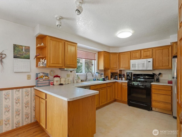 17417 29th Dr SE, Bothell, WA 98012 - kitchen featuring white microwave, black gas range, a sink, a peninsula, and freestanding refrigerator